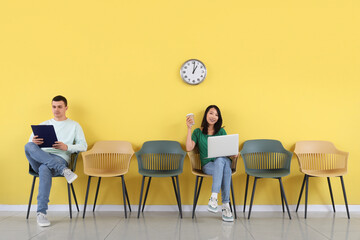 Applicants waiting for job interview near yellow wall in room