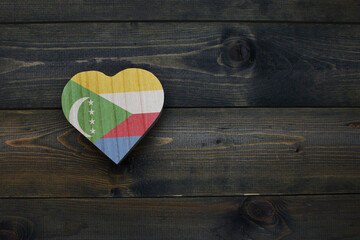 wooden heart with national flag of comoros on the wooden background.