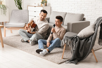 Father with his little son playing guitar and singing at home