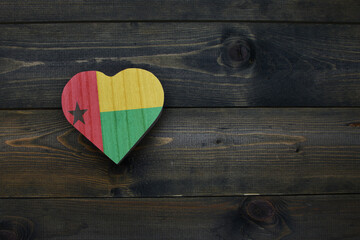 wooden heart with national flag of guinea bissau on the wooden background.