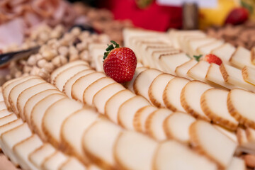 A strawberry on top of slices of cheese.  cheese with fruit on the aperitif table. Food, appetizers...