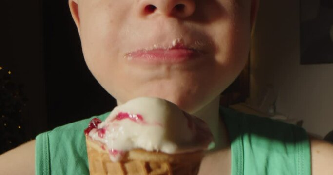 Close-up of child's mouth, a little boy eating a waffle cup with vanilla ice cream and strawberry ice cream. Close up portrait of cute boy eating waffles cone ice cream. Child licking ice cream. 4K