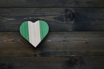 wooden heart with national flag of nigeria on the wooden background.