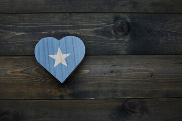 wooden heart with national flag of somalia on the wooden background.