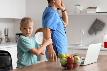 Busy mature doctor with his upset little son in kitchen
