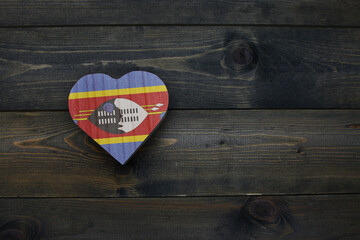 wooden heart with national flag of eswatini on the wooden background.