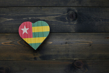wooden heart with national flag of togo on the wooden background.