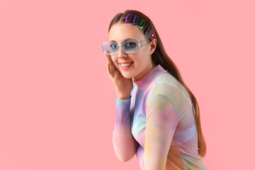 Young woman in sunglasses with hair clips on pink background