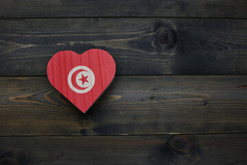 wooden heart with national flag of tunisia on the wooden background.