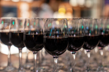 Wine glasses filled with red wine arranged and presented on a table top for self-service by party guests. Shallow depth-of-field image. A glass of red wine is on the table. Glasses of wine. 
