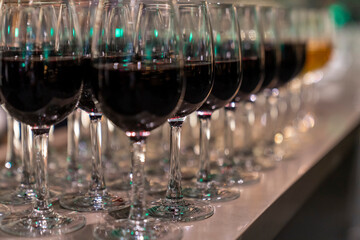 Wine glasses filled with red wine arranged and presented on a table top for self-service by party...