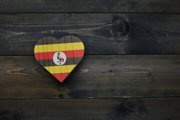 wooden heart with national flag of uganda on the wooden background.