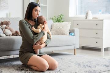 Tired young woman with her baby suffering from postnatal depression at home
