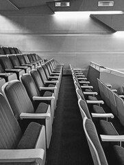 Interior of a modern auditorium with rows of chairs in black and white
