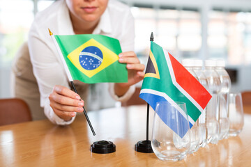 Little flag of South Africa on table with bottles of water and flag of Brazil put next to it by...