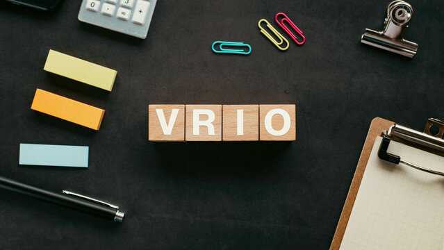 There is wood cube with the word VRIO. It is an abbreviation for Value, Rarity, Inimitability, Organization as eye-catching image.