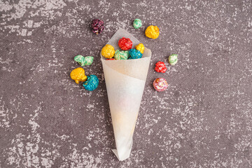 Paper cone with sweet colorful popcorn on dark background