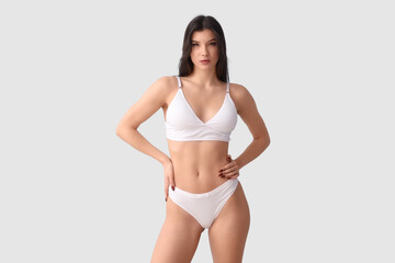 Fototapeta premium Pretty young woman in white underwear on blue background