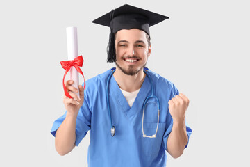 Male medical graduate student with diploma on white background