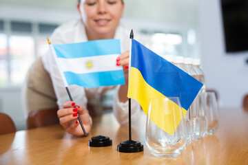 Preparation for international negotiations. Office coordinator setting national flags of Ukraine...
