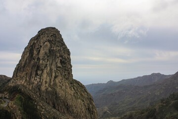 A majestic rock formation resembling a serene face, etched with the marks of time, set against a...