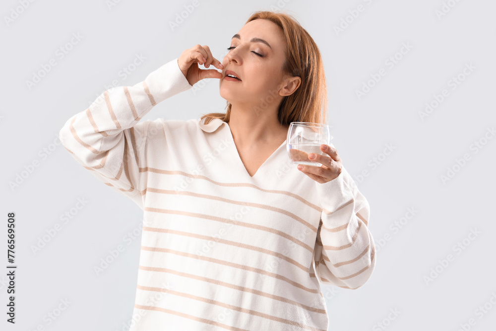 Canvas Prints Mature woman taking pill on light background. Menopause concept