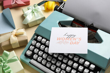 Typewriter, tulips, postcard and gift boxes on beige background. Womens Day concept