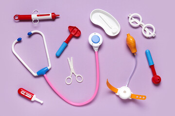 Toy stethoscope with thermometer and  reflex hammer on lilac background. Top view