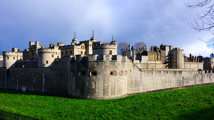 Panoramic external view of walls and towers of Tower of London under dark sky