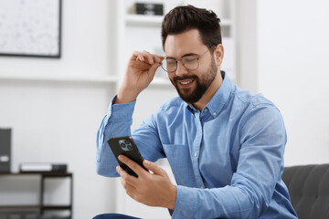 Handsome young man using smartphone in office