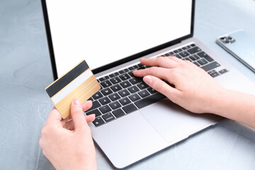 Online payment. Woman with laptop and credit card at white table, closeup