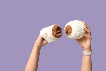 Female doctor's hands with knitted model of breast on purple background. Breast feeding concept