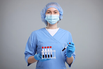 Laboratory testing. Doctor with blood samples in tubes on light grey background