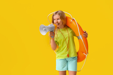Happy little girl lifeguard with ring buoy and megaphone on yellow background