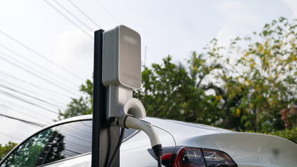EV electric car recharge battery at parking lot in natural green city park. Alternative clean...