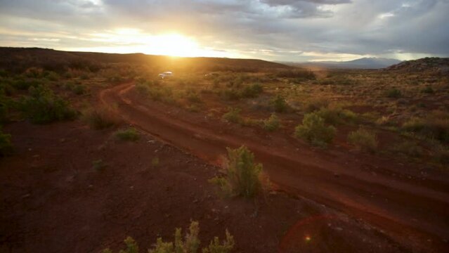 SUV's driving in red dirt of Southern Utah - sunset drone shot