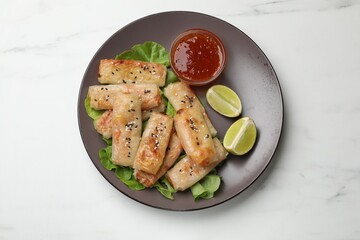 Tasty fried spring rolls and sauce on white marble table, top view