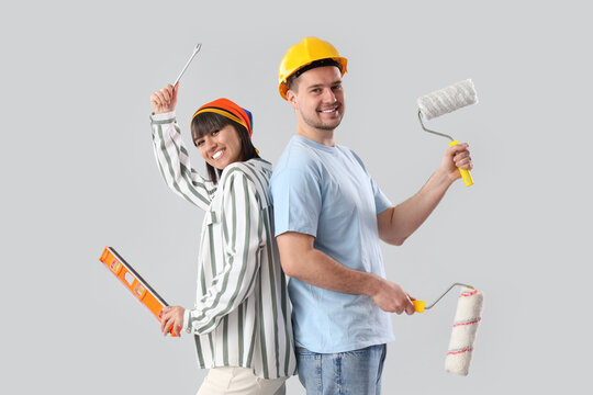 Young couple with tools on light background. Repair concept