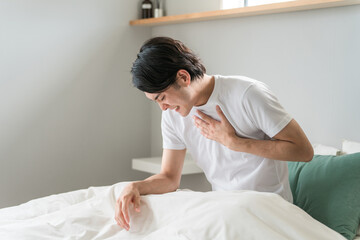 ベッドの上で胸を苦しがる急病の男性（苦しい・発作・心筋梗塞・心臓発作・動悸・狭心症）
