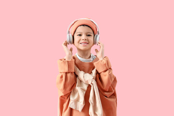 Cute little Asian boy in adult clothes with headphones on pink background