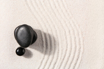 Fototapeta na wymiar Stones on sand with lines in Japanese rock garden, top view. Zen concept