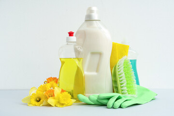 Cleaning supplies with tools and spring flowers on white background