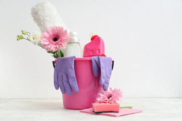 Bucket with cleaning supplies, tools and spring flowers on white background - obrazy, fototapety, plakaty