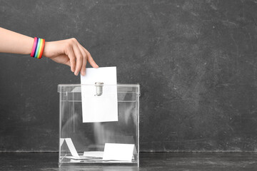Voting woman near ballot box on table against black background
