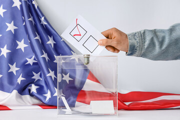Voting man near ballot box on table and flag of USA against white background