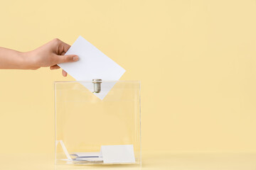 Voting woman near ballot box on table against yellow background