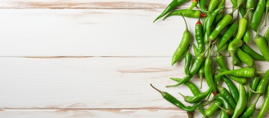 Fresh green chili peppers neatly arranged on a rustic white wooden surface for a vibrant and natural display