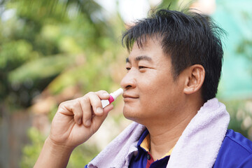 Asian man use menthol inhaler to smell for relief symptom of dizzy from hot weather condition....