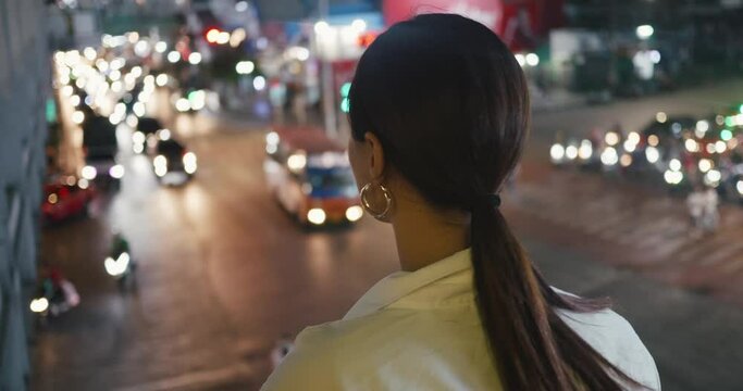 Evening falls woman looks modern city's lively traffic back view close-up Traffic symbol of continuous movement. Traffic weaving fabric of futuristic city In city that's always awake.