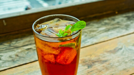 view of iced tea with lemon leaves on wooden table